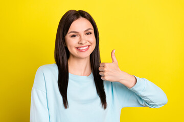 Wall Mural - Photo portrait woman smiling happy showing thumb-up sign wearing jumper isolated vibrant yellow color background