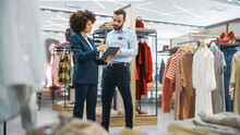 Clothing Store: Businesswoman Uses Tablet Computer, Talks To Visual Merchandising Specialist, Collaborate To Create Stylish Collection. Small Business Fashion Shop Sales Manager Talks To Designer.