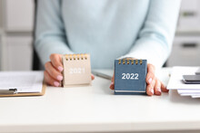Woman Holds Calendar For 2021 And 2022 While Sitting At Desk