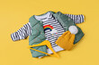Waistcoat down jacket with striped jumper on yellow background. Stylish childrens outerwear. Fashion kids outfit.