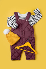 Wall Mural - Warm pants and striped jumper with hat on yellow background. Set of baby clothes for winter. Fashion kids outfit.