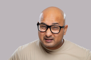 Wall Mural - Portrait of a bald man wearing eyeglasses with confused expression against plain background.
