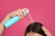 © New Africa - Young woman applying dry shampoo against pink background, closeup