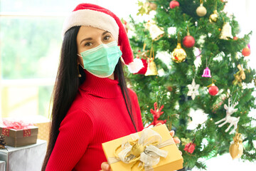 Female in red shirt and santa hat wear face mask for protection from Covid-19 in new Christmas event and party in house