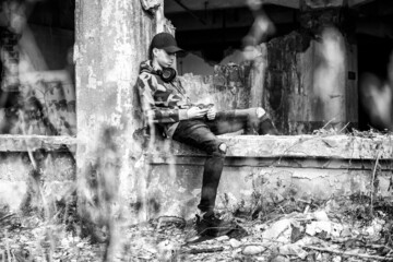 Sticker - Young boy sitting on a crumbling building and using smarthphone