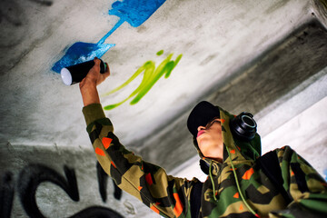 Wall Mural - Boy in a hood spraying the wall. Graffiti concept