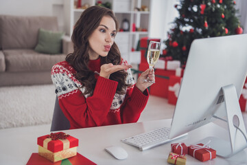 Wall Mural - Photo portrait woman in sweater smiling drinking champagne sending air kiss on video connection