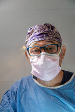 Senior Doctor In Surgical Suit And Mask In Clinic