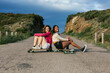 © ADDICTIVE STOCK - Happy diverse women sitting on longboard on road