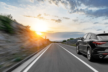 Gray car on a scenic road. Car on the road surrounded by a magnificent natural landscape in the rays of sunset or dawn.