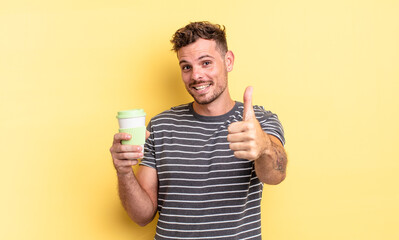 young handsome man feeling proud,smiling positively with thumbs up take away concept