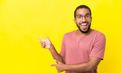 Wall Mural - Young latin man isolated on yellow background surprised and pointing side