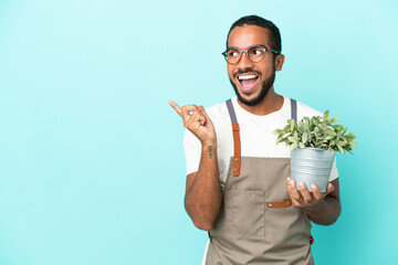 Canvas Print - Gardener latin man holding a plant isolated on blue background intending to realizes the solution while lifting a finger up