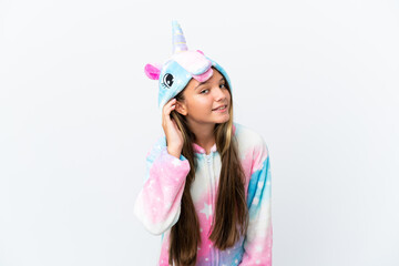 Poster - Little caucasian girl wearing unicorn pajama isolated on white background listening to something by putting hand on the ear