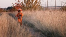 Funny Child Boy In Orange Fluffy Lion Costume Running To Camera On Yellow Fall Grass. Cute Happy Toddler Walking With Sincere Smile Alone On Autumn Background. Halloween, Trick Or Treat. 