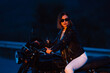© kohanova1991 - Hipster stylish motorcyclist woman sitting on vintage-styled motorcycle. Young female driver night on roadway. Trip, freedom, classic motorbike concept.