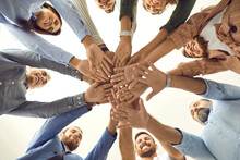 Human Support. Bottom View Of A Group Of Different People Standing In A Circle And Folding Their Arms Together As A Symbol Of Cooperation. Friends Or Business Partners Demonstrate Unity And Teamwork.