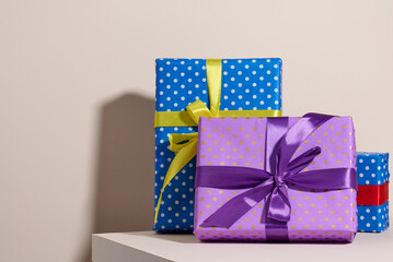 Wall Mural - box packed in festive purple paper and tied with silk ribbon on a beige background, birthday gift, surprise