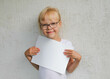 An emotional child holds a white sheet in his hands, on a gray background. High quality photo