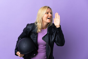 Wall Mural - Middle age woman holding a motorcycle helmet isolated on purple background shouting with mouth wide open to the side