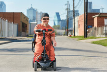 Portrait Of Male Dwarf In The Street In Texas Riding A Mobility Scooter, Smoking A Cigarette