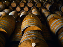 Wooden Wine Barrels Stacked On Top Of Each Other In Cellar