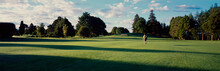 Panorama Of Back View Of Man Walk Across Pristine Golf Course
