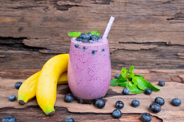 Wall Mural - Blueberry mix banana smoothies purple colorful fruit juice milkshake blend beverage healthy high protein taste yummy drink in glass morning on wooden background.