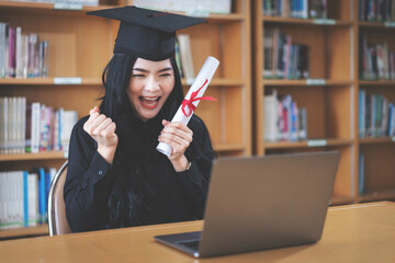 Poster - Young university student expressing joy and excitement for graduation in front of a laptop.