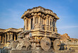 Richly sculpted stone chariot with clear blue sky background in Hampi, Karnataka.