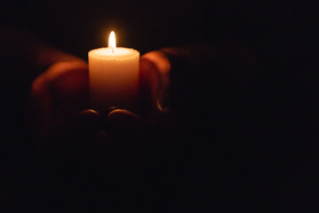 Wall Mural - Hands holding burning candle in dark like a heart.Selective focus,black background.Copy space.