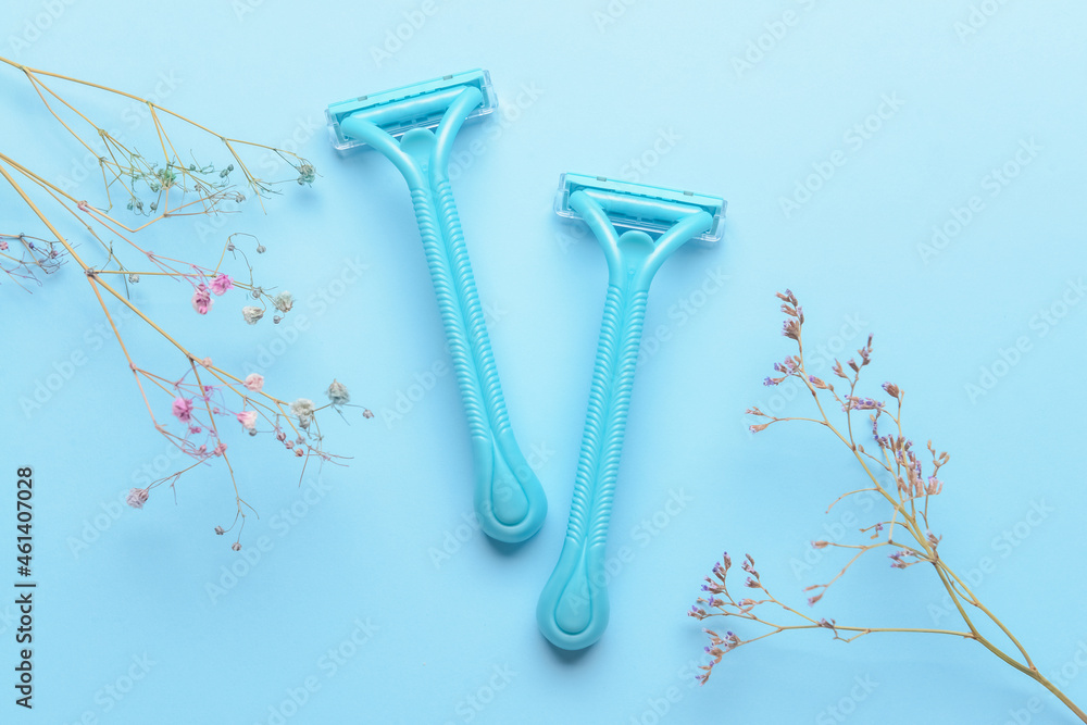 Safety razors and flowers on blue background
