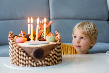 Poster - Cute child, boy, celebrating his birthday at home with colorful cake