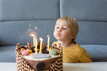 Poster - Cute child, boy, celebrating his birthday at home with colorful cake