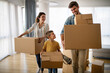 © NDABCREATIVITY - Happy family with children moving with boxes in a new apartment house.