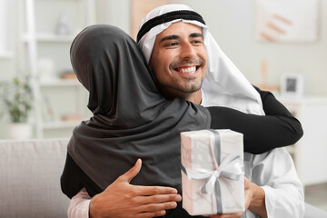 Wall Mural - Young Muslim woman greeting her husband at home