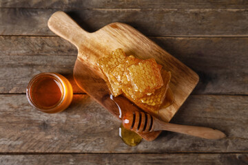 Jar of honey, combs and dipper on wooden background