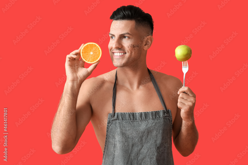 Young man with orange and apple on color background. Vegan Day