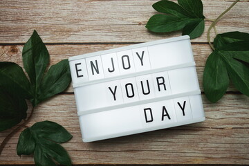 Wall Mural - enjoy your day text on lightbox on wooden background