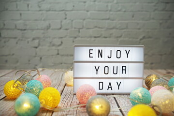 Wall Mural - enjoy your day text on lightbox on wooden background