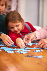 Wall Mural - Close Up Of Grandchildren With Grandparents Sit Around Table At Home Doing Jigsaw Puzzle Together