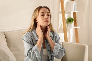 Young woman doing thyroid self examination at home