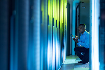 African american male computer technician using tablet working in server room