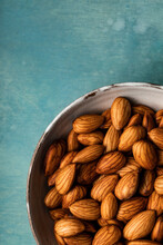 A Closeup Overhead View Of A Bowl Of Almonds Shot On A Blue Background