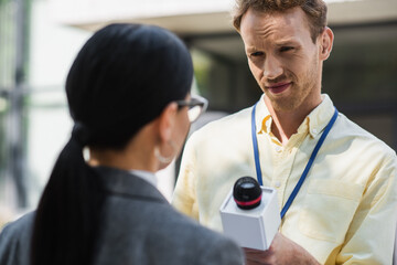 Canvas Print - reporter taking interview with blurred businesswoman in glasses