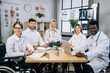 © sofiko14 - Multiracial medical practitioners in uniform smiling and looking at camera during conference meeting at bright office. Female doctor using wheelchair coworking with her colleagues at hospital.