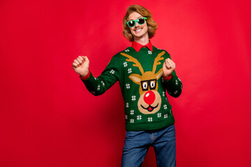 Poster - Photo of sweet shiny young man wear green sweater spectacles smiling dancing isolated red color background