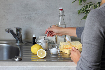 Vinegar, baking soda, lemon, natural sponge, toothbrush and towels on the kitchen sink. DIY Cleaning with natural products. Zero waste.