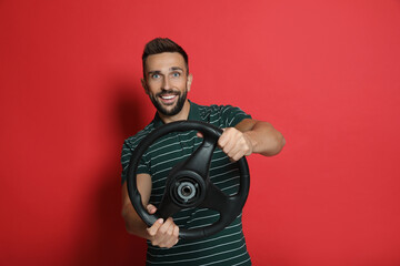 Wall Mural - Happy man with steering wheel on red background