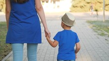 Mom Leads Boy By Hand, Custody Of Little Child, Happiness Of Motherhood With Her Son, Mother Walks With Kid In City Park In Open Air, Life With Parent, Look After And Take Time For Baby On Weekends